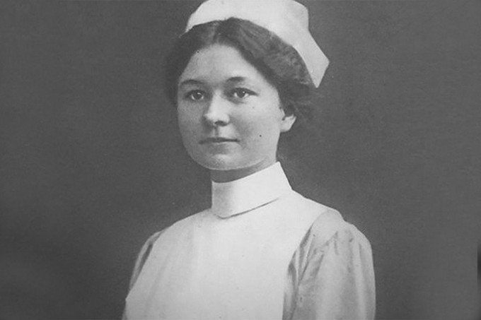 Helen Fairchild in nursing uniform and cap stands smile at the camera