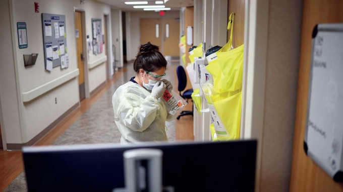 Nurse is putting on an isolation gown, gloves, and mask