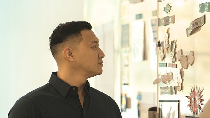 Registered Nurse Jonathan Lee stands with his profile to the camera, looking at a poster board with pieces of paper on it.