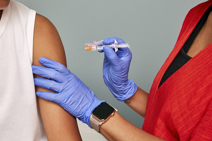 A nurse is holding a needle near a patient's arm and getting ready to give a vaccine