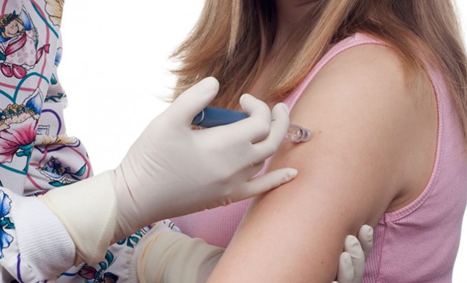 Nurse is giving a shot to a female patient in her left arm