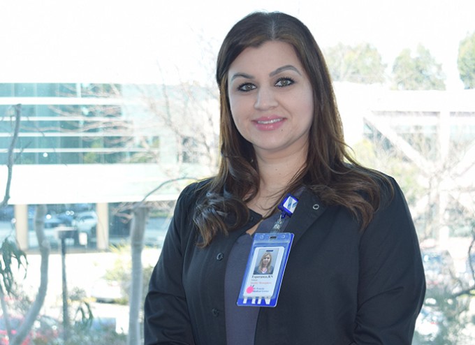 Registered Nurse Esperanza Salazar stands smiling with a badge on and St. Francis Medical Center behind her