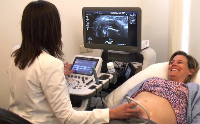 Nurse practitioner is performing an ultrasound on a female patient who is lying down