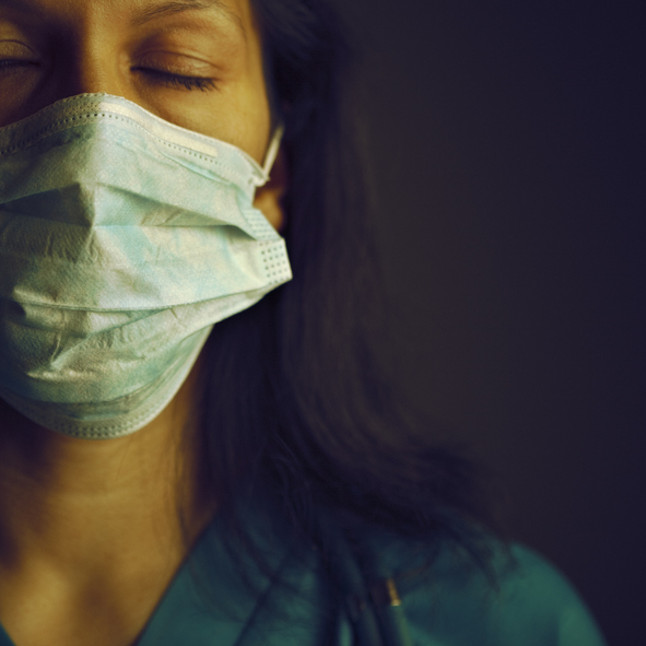 Female nurse wearing a mask has her eyes closed and is breathing
