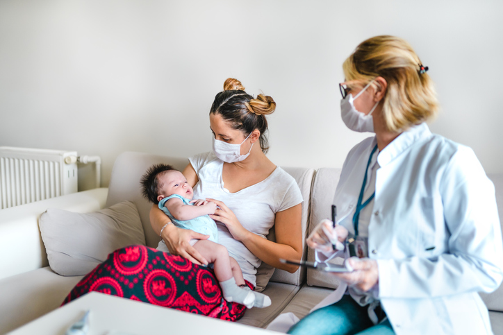 Nurse practitioner is sitting next to a female patient who is holding her baby