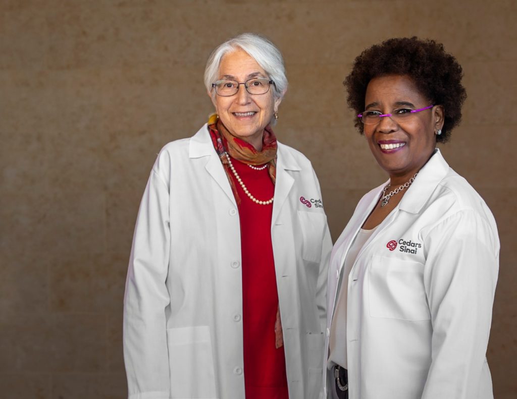 Bernice Coleman and Harriet Aranow stand side by side in white coats smiling