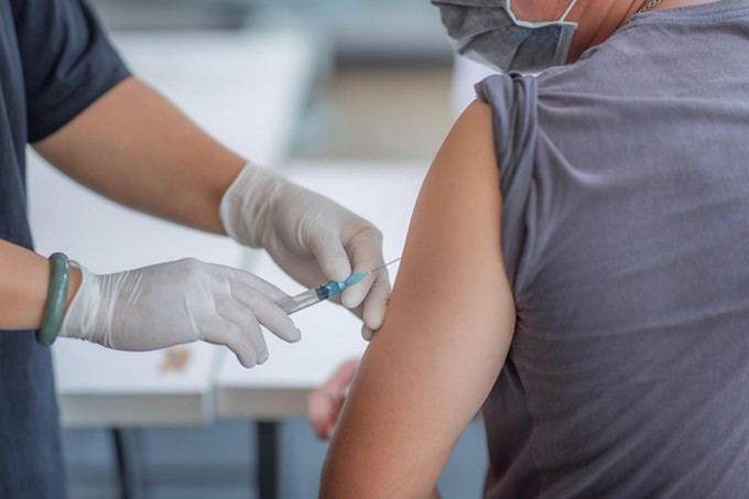 A nurse is giving a young adult a vaccination