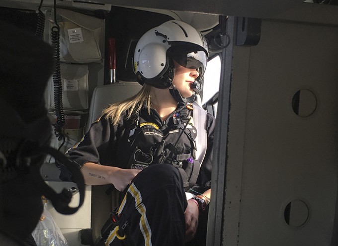 Registered Nurse Carole Covey sitting in a plane with a jumpsuit on and a helmet. She is looking out of the window.