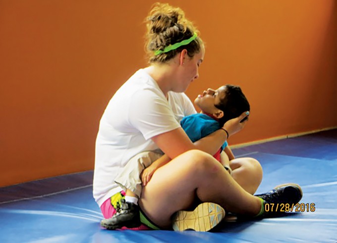 A woman is sitting on the ground crosslegged holding a child in her arms