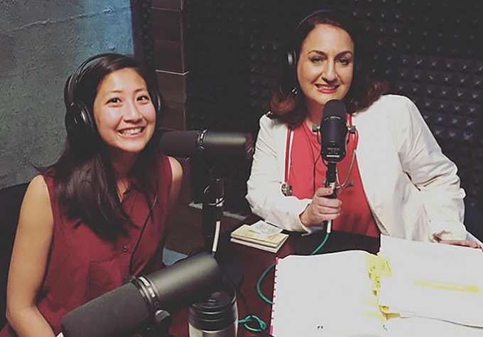 Two nurses are smiling in casual clothing around microphones. Both are wearing headphones.