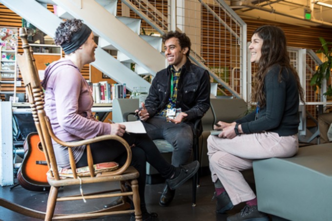 Three students are sitting in a circle laughing together