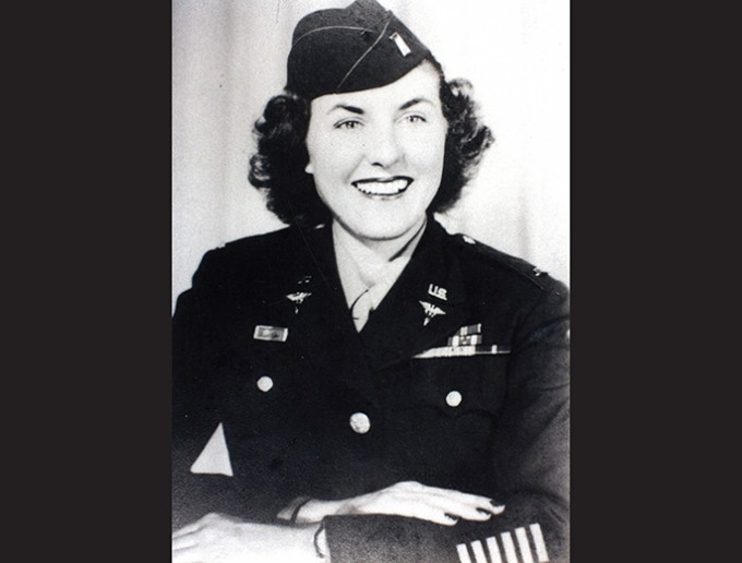 Mildred Dalton wearing a military uniform and hat, sits smiling towards the camera