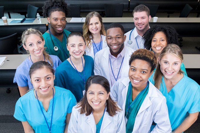 A group of hospital personnel are smiling and looking at the camera