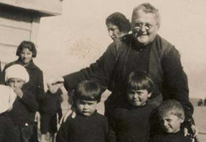 Emma Cushman poses with three children. They are all wearing black outfits.