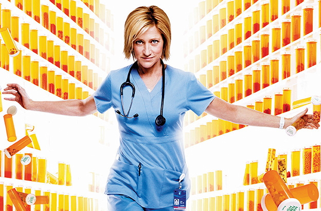 Nurse Jackie walking towards camera wearing scrubs and stethoscope with pills surrounding her