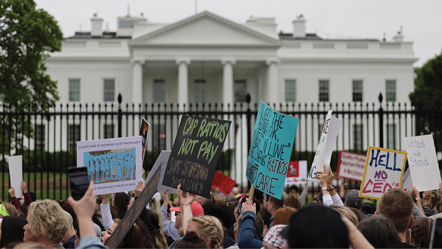 People are protesting with signs outside the gates of the White House