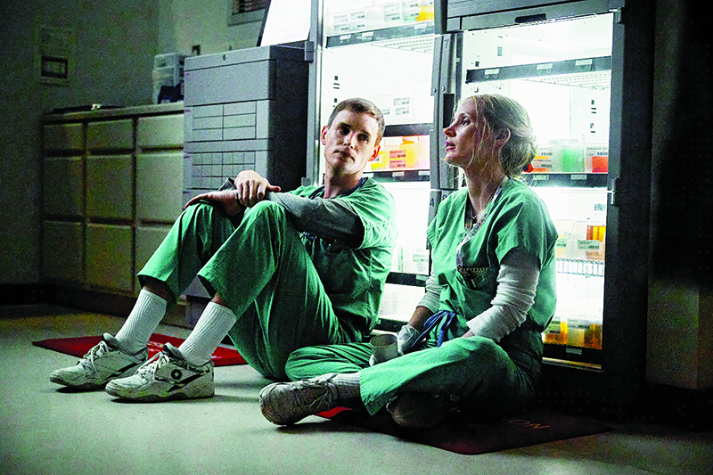 Jessica Chastain and Eddie Redmayne from a scene in The Good Nurse sitting on the ground talking