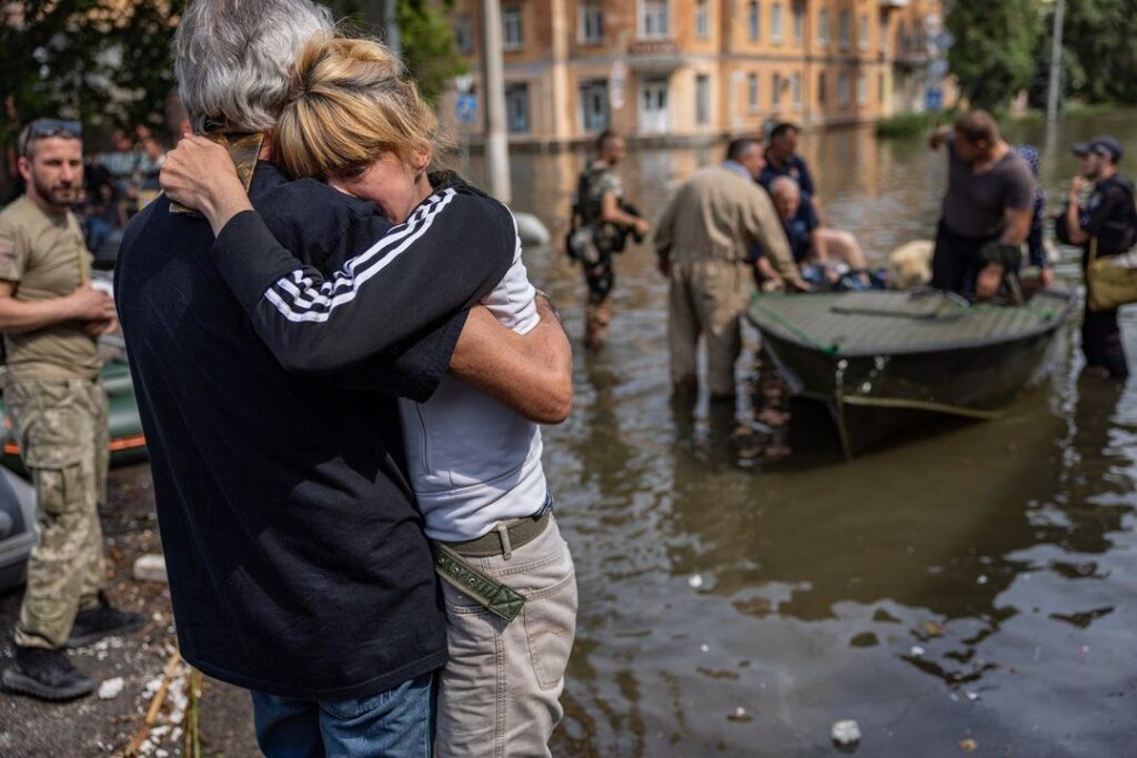 People hugging while standing in flood zone in Ukraine.