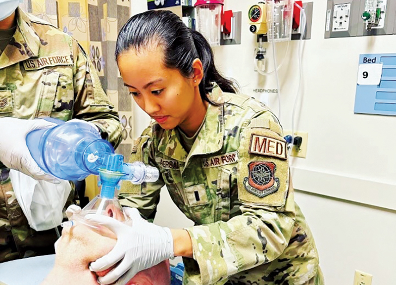 U.S. Air Force nurse holding a patient's head while another nurse intubates the patient.