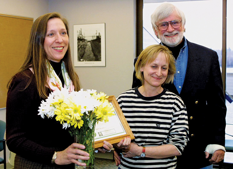Bonnie and Mark Barnes present the first DAISY Award and bouquet of white and yellow daisies to a nurse.