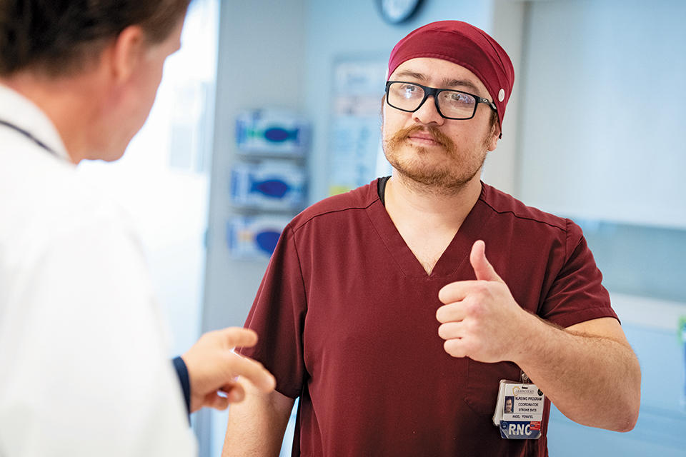 Stroke Program Coordinator Angel Penefiel wearing maroon scrubs with a thumbs up