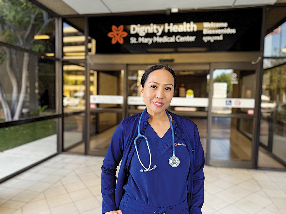 Med-Surg nurse wearing blue scrubs in front of hospital